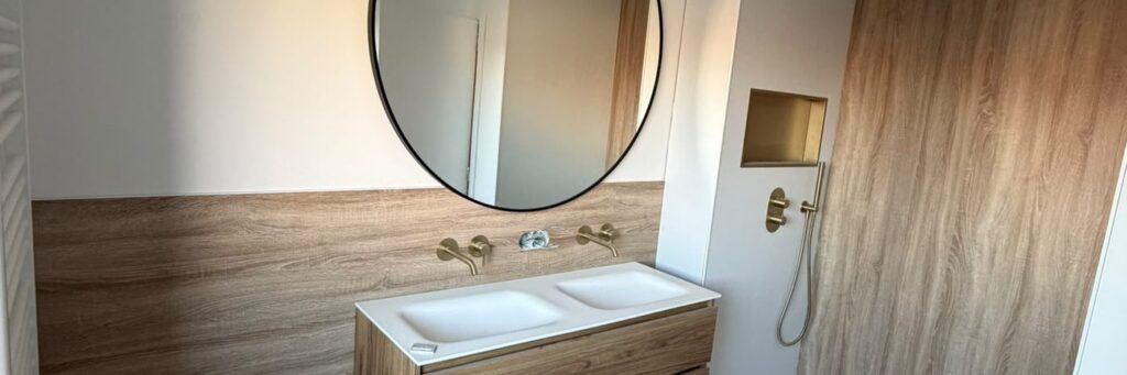Gerenoveerde badkamer met dubbele wastafel en ronde spiegel
